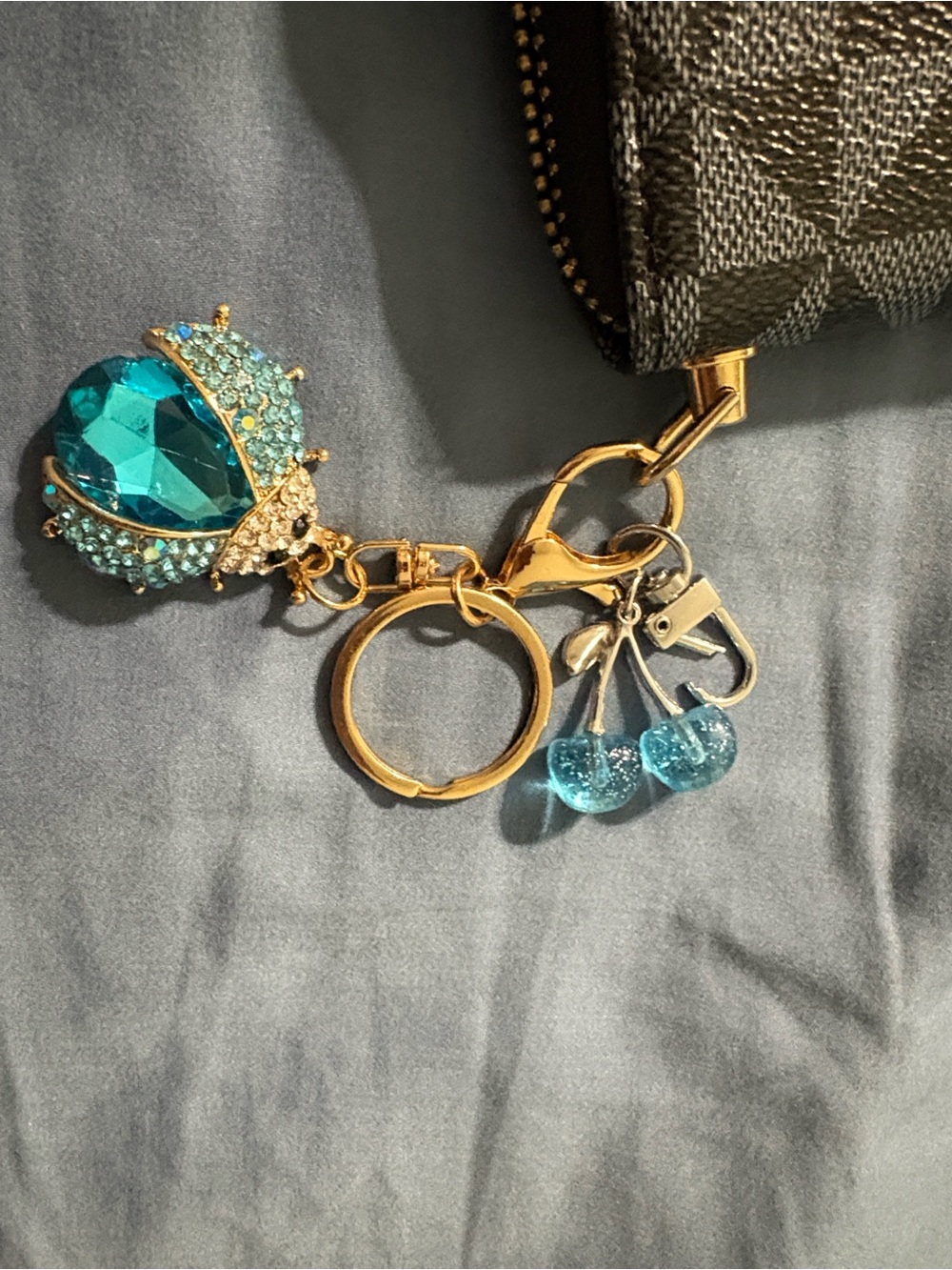 Blue Crystal Beetle Keychain with blue Cherry Charms on black geometric wallet.